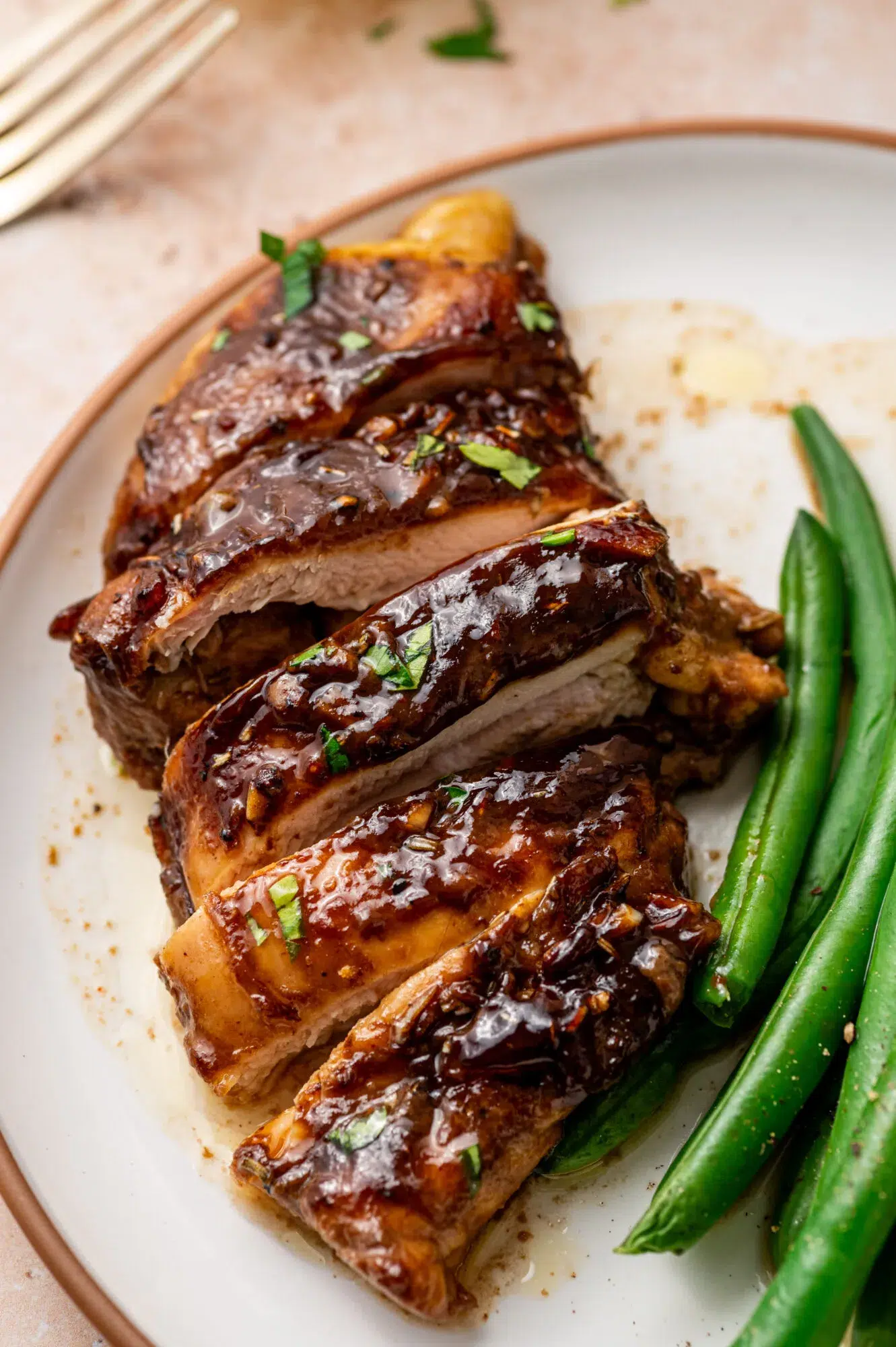 Sliced balsamic Dijon mustard chicken thighs with a side of green beans.