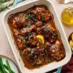 Balsamic Dijon mustard chicken thighs in a baking dish surrounded by ingredients.