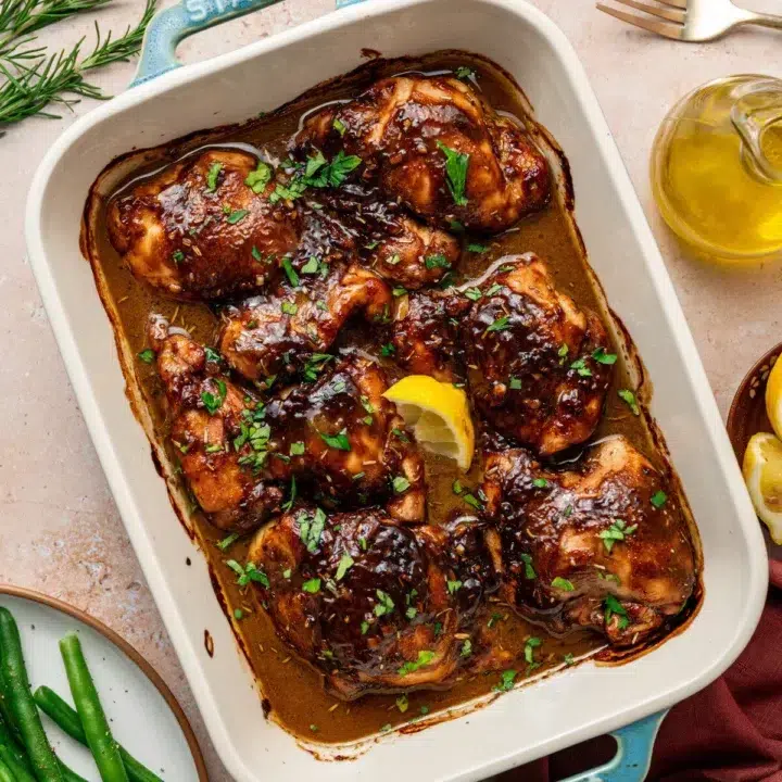 Balsamic Dijon mustard chicken thighs in a baking dish surrounded by ingredients.