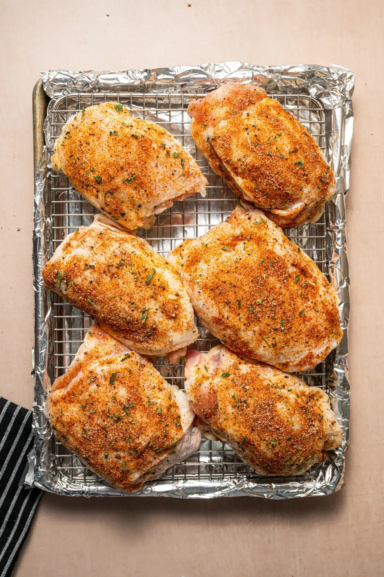 seasoned raw chicken thighs on a baking dish ready to go in the oven.