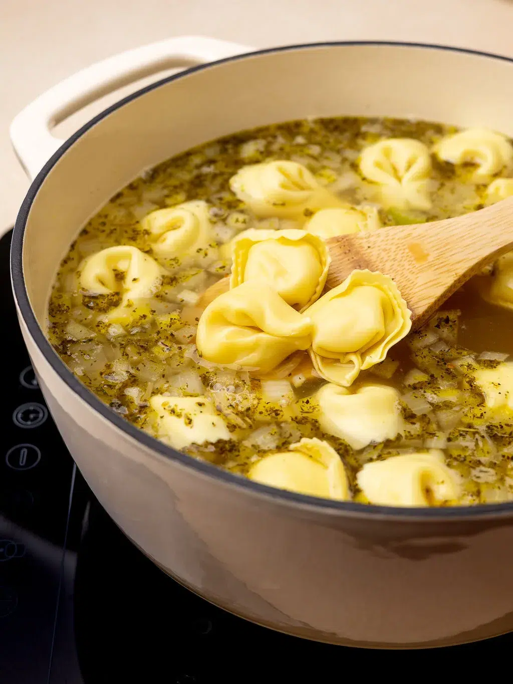 A Dutch oven with broth cooking tortellini.