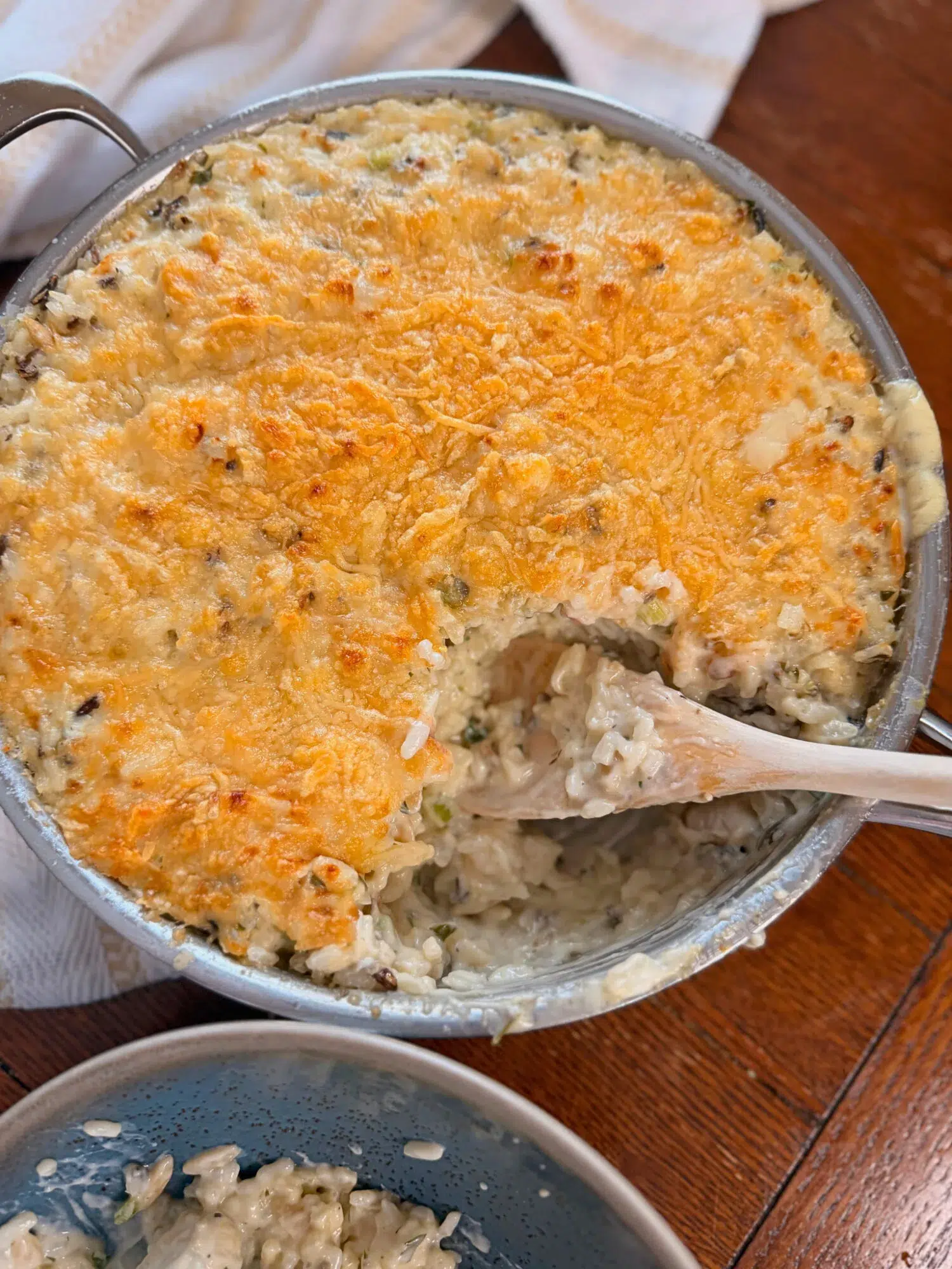 A piece taken out of a chicken wild rice bake with a wooden spoon.