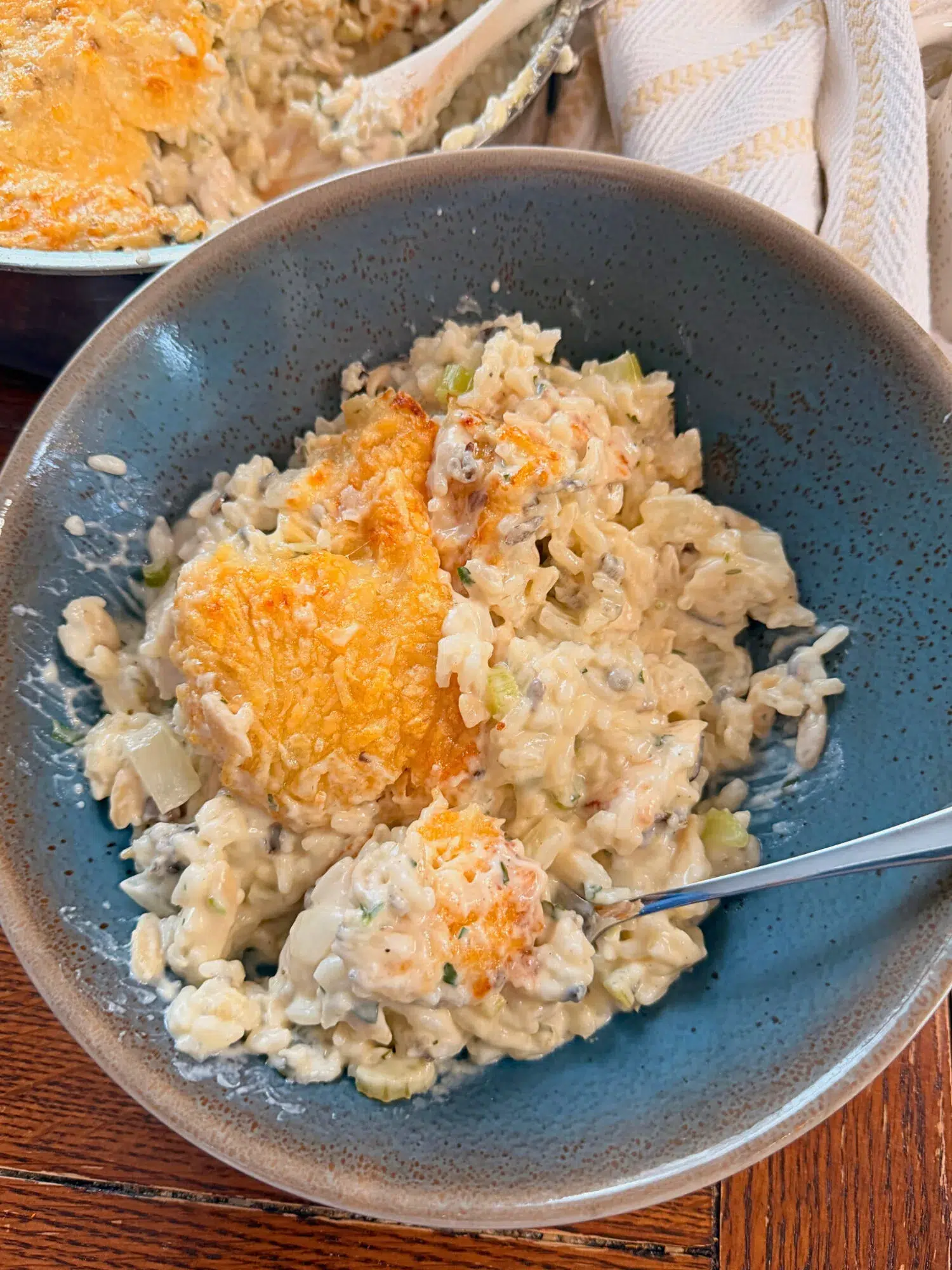 A serving of chicken wild rice bake in a blue bowl with a fork.