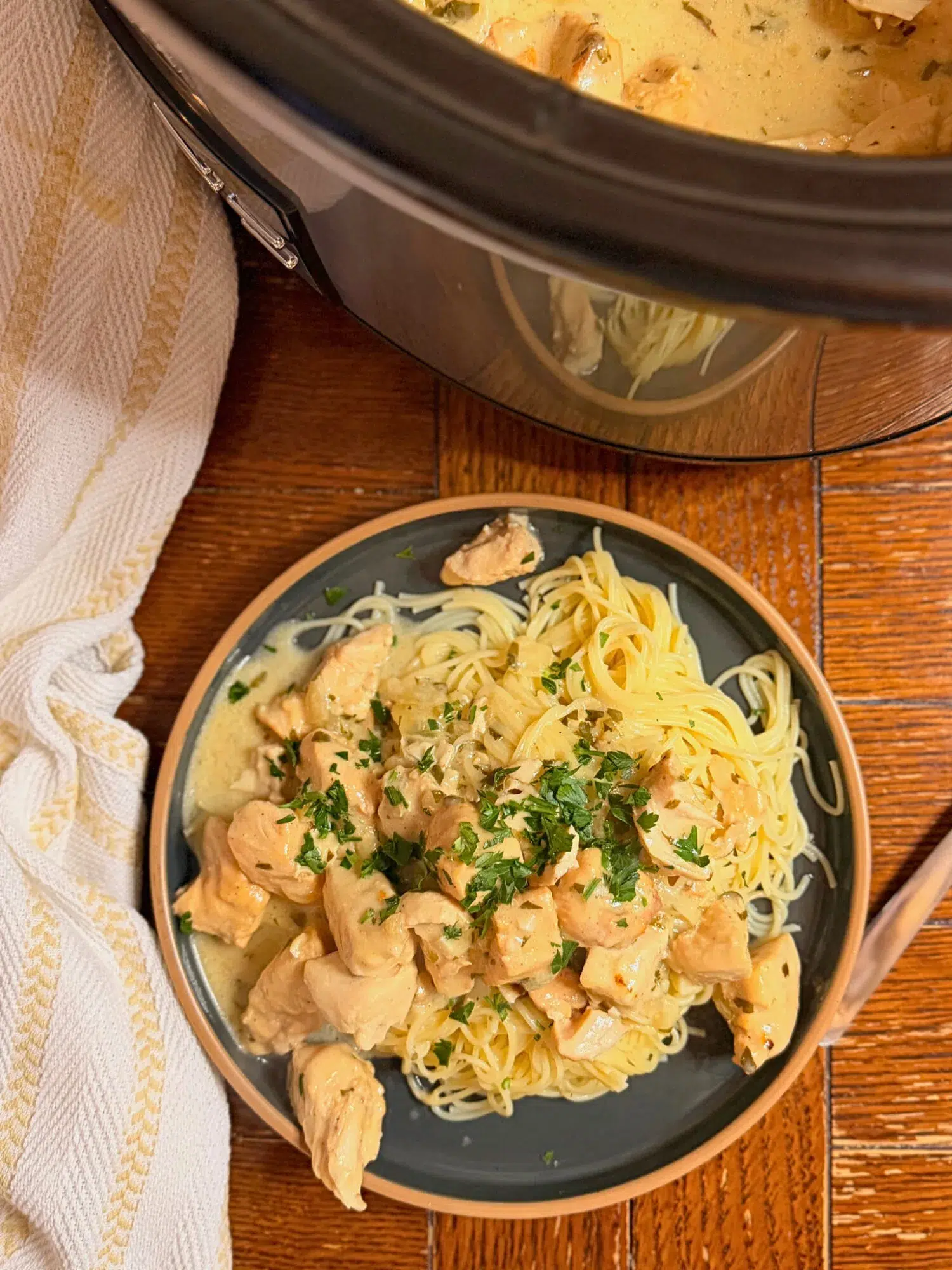 Slow cooker creamy garlic chicken on a plate with noodles.