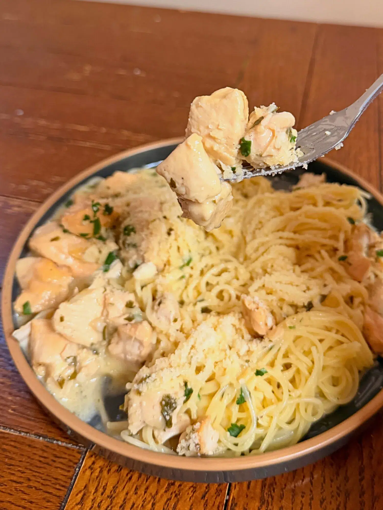 A forkful of creamy garlic chicken over a plate of noodles.