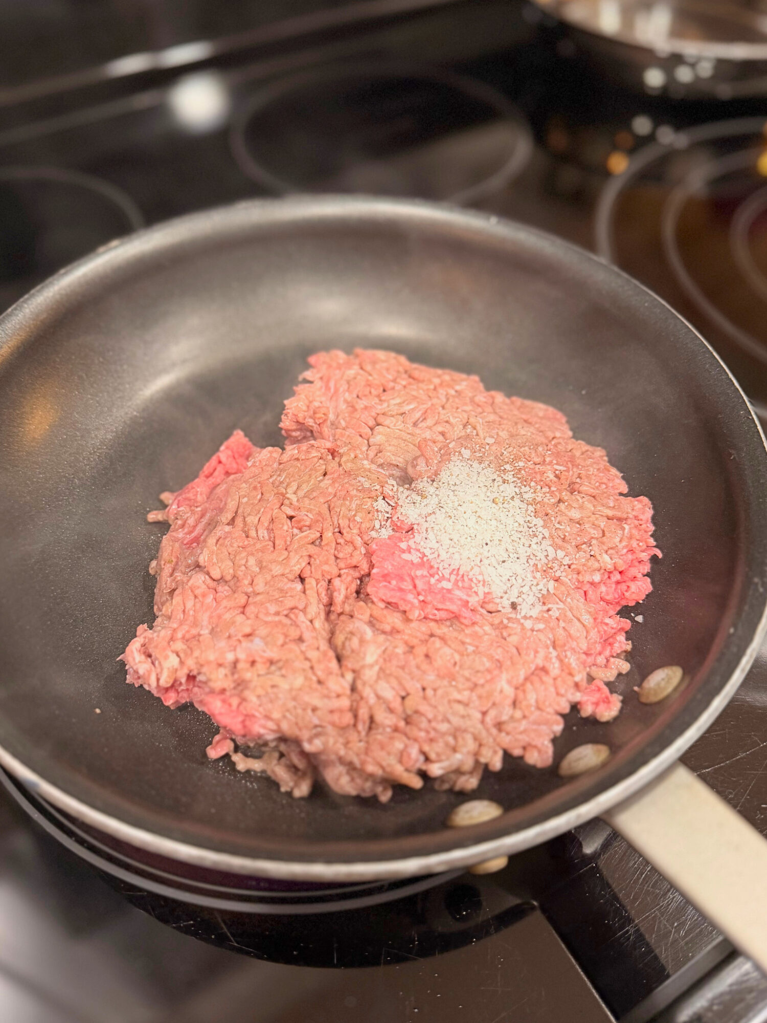 Ground beef and salt in a skillet before browning.