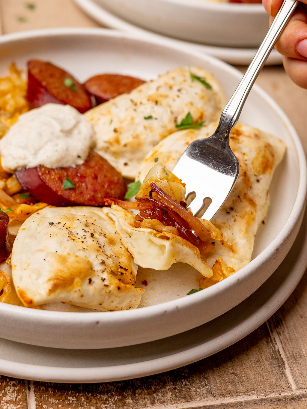 Digging a fork into a pierogi and kielbasa sausage.