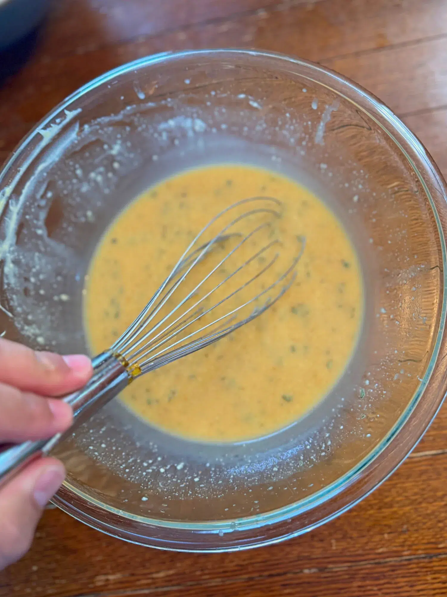 Whisking a yellow sauce in a glass bowl.