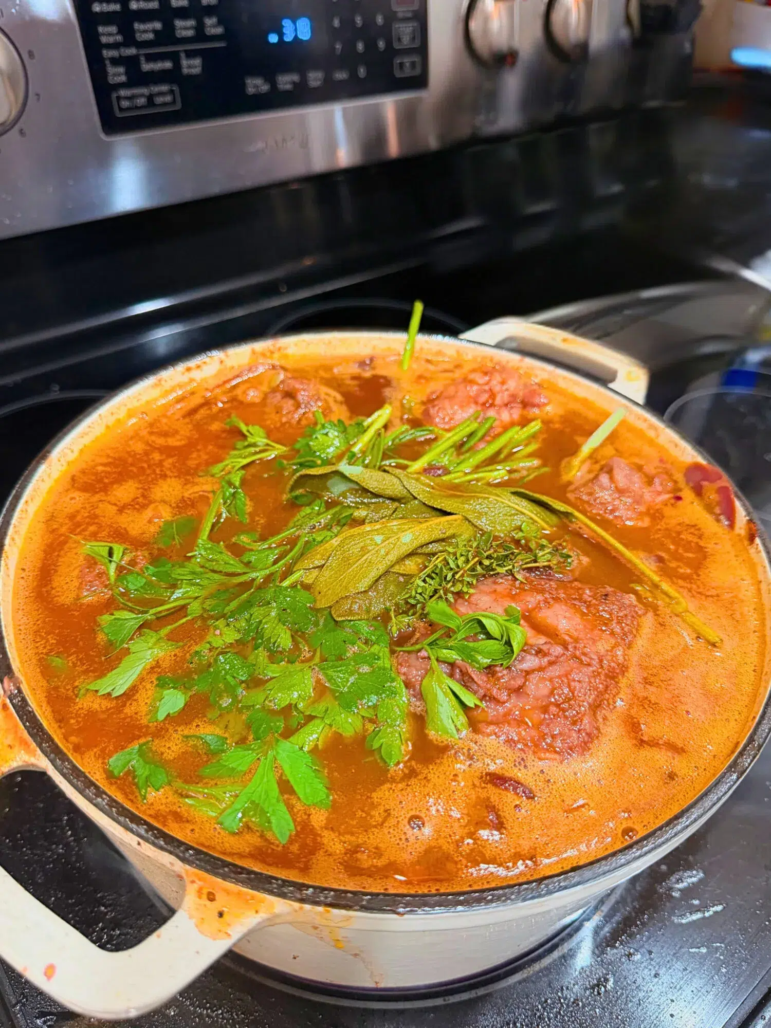 Fresh parsley on top of braising short ribs in a Dutch oven.