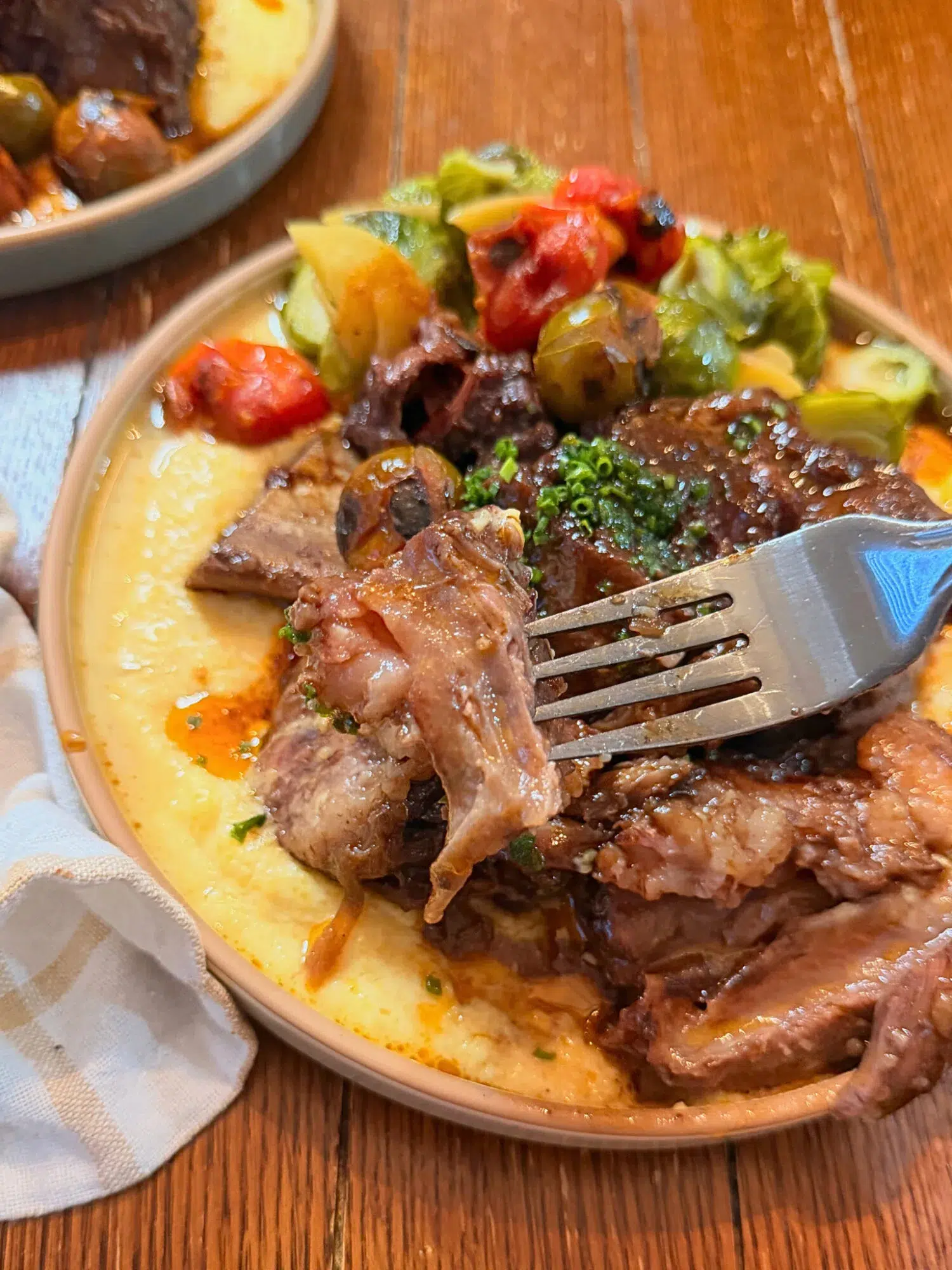 A forkful of short ribs hovering over a serving of short ribs.