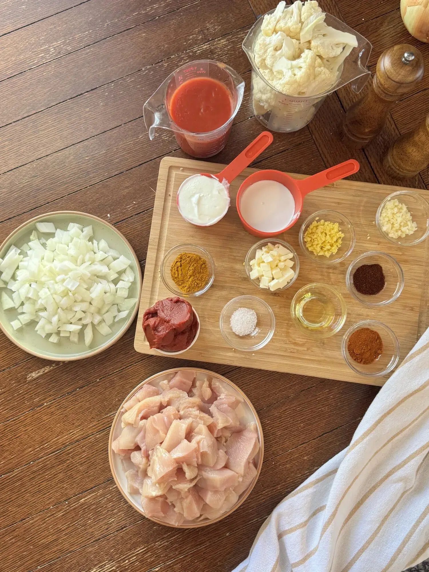 Ingredients for slow cooker butter chicken on a wooden table.