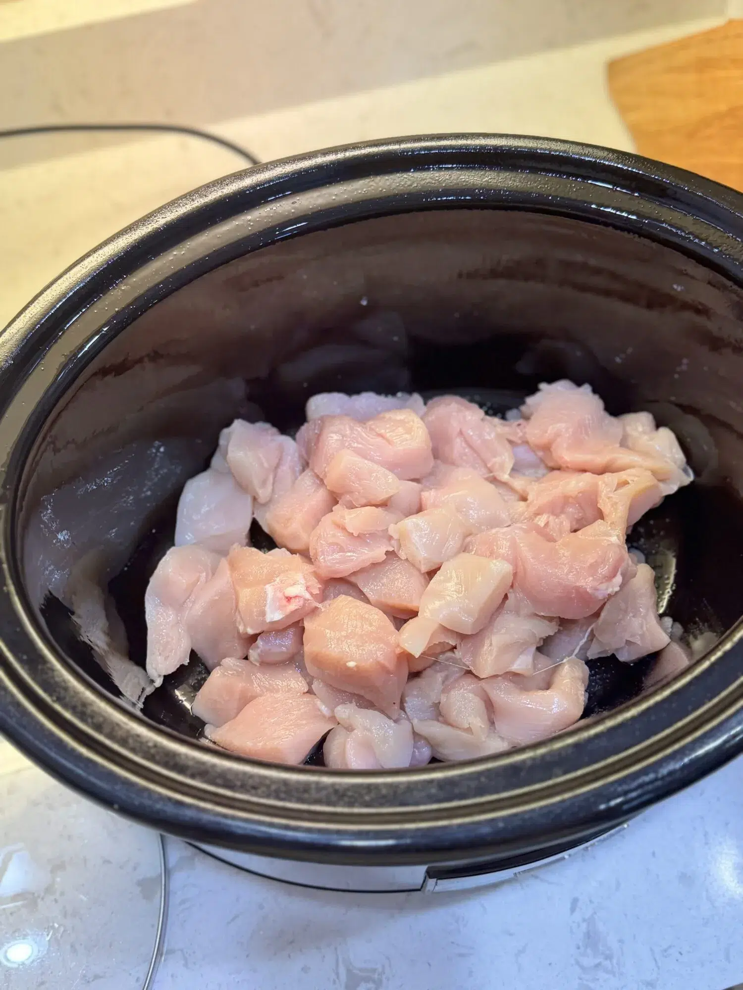 Raw chicken pieces in a slow cooker.