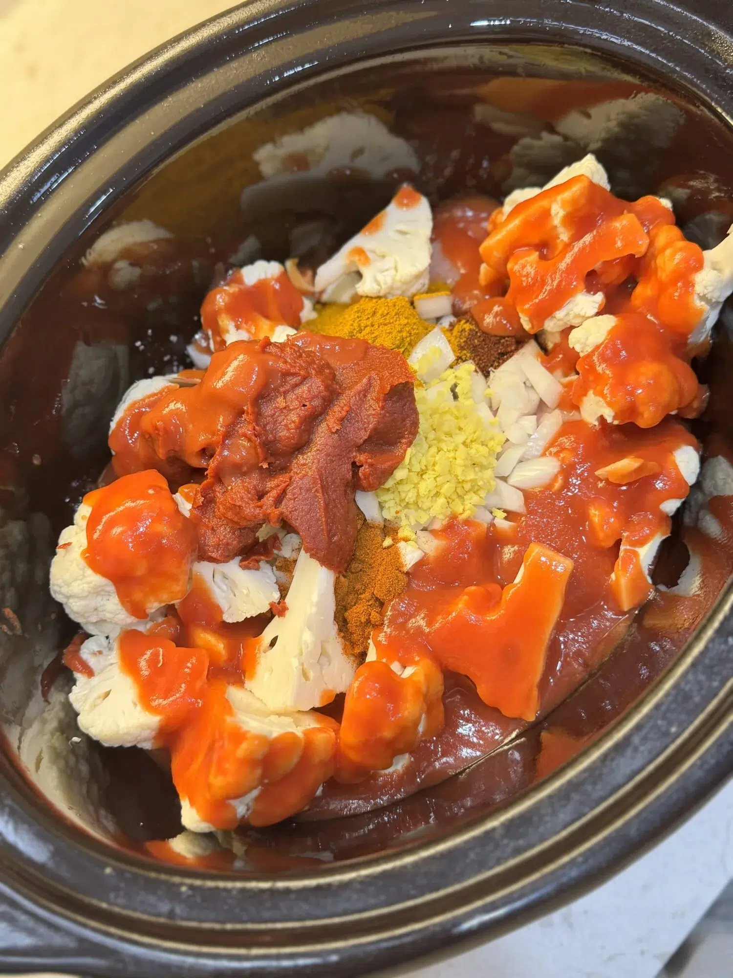 Adding spices and sauce to chicken in a slow cooker.
