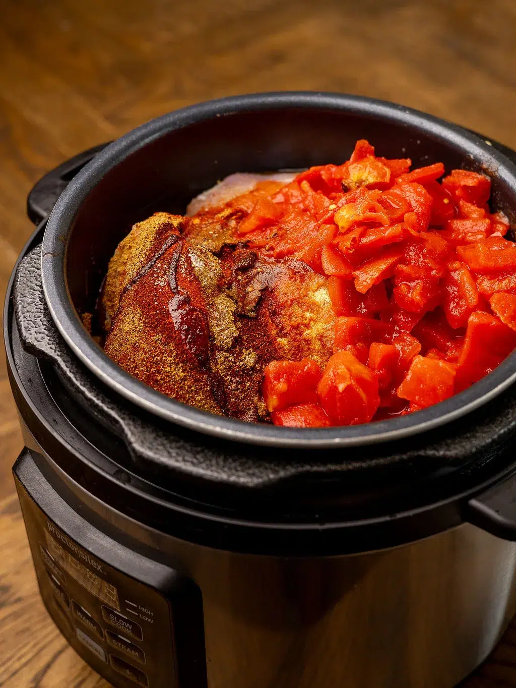 Chicken and diced tomatoes in a slow cooker.