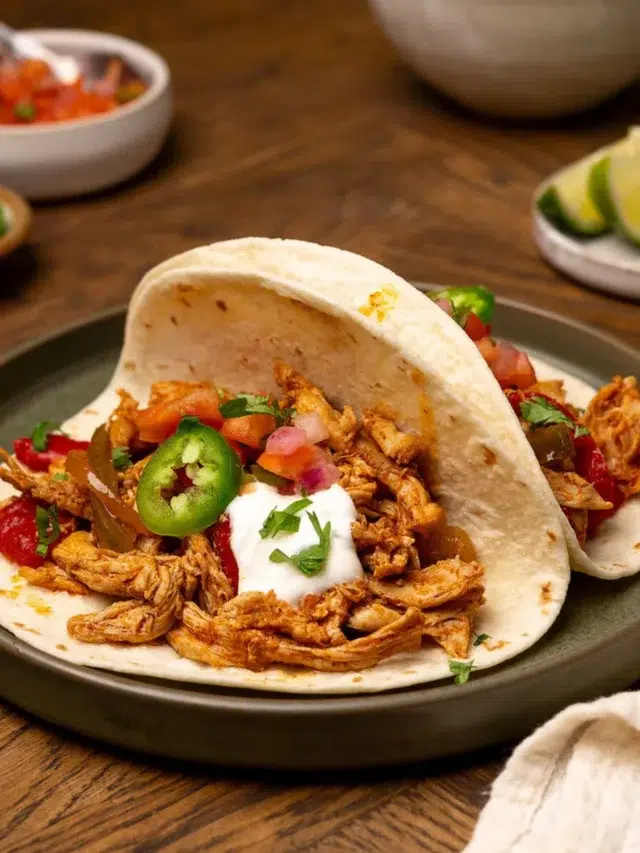 Slow cooker chicken fajitas on a black plate.