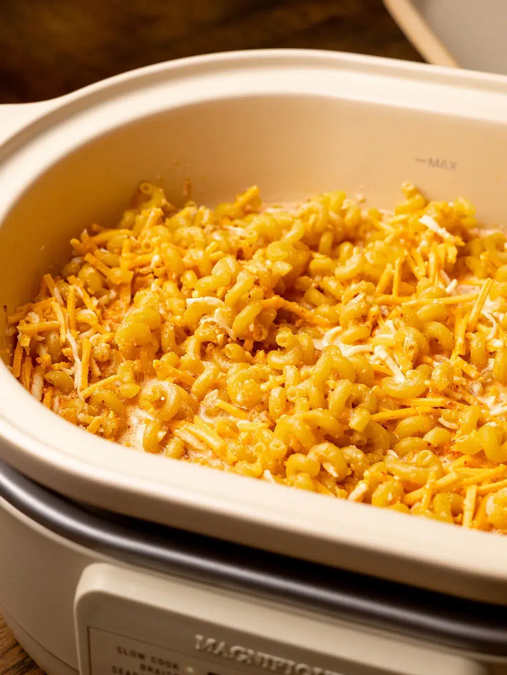 Noodles and shredded cheese in a slow cooker.