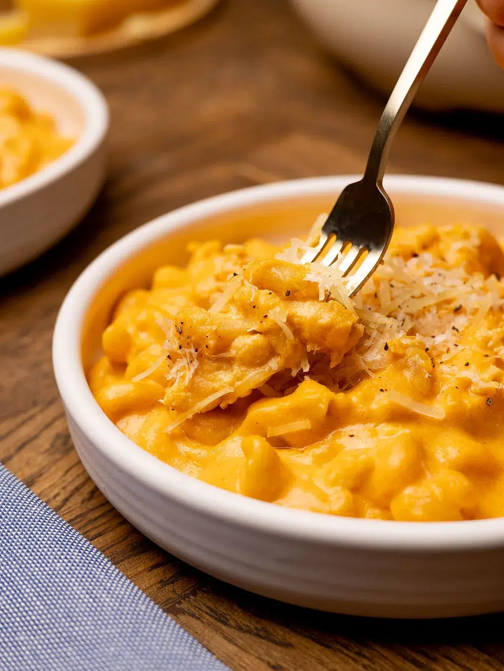 A fork dipping into a white bowl of slow cooker mac and cheese.