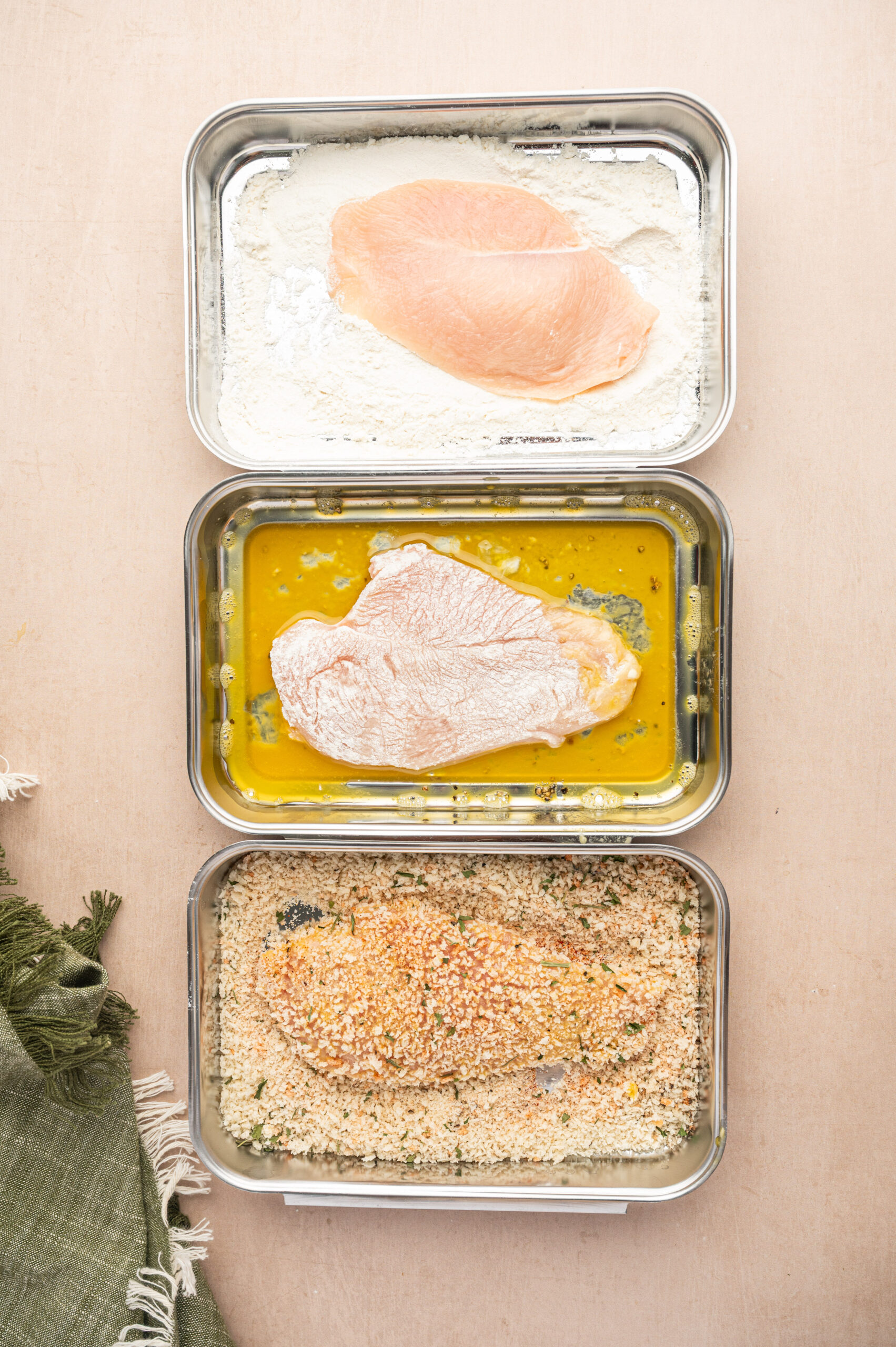 Dipping chicken cutlets into shallow dishes of eggs, flour, and breadcrumbs.