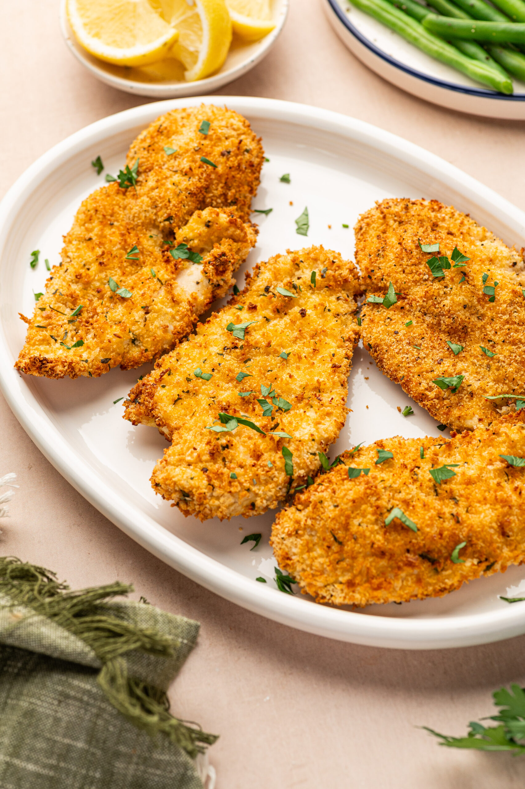 Air fryer chicken cutlets on a white serving plate.