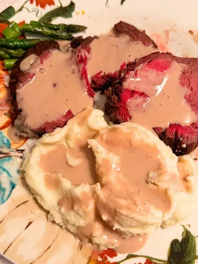 Beef tenderloin sauce on a decorative plate of beef tenderloin and mashed potatoes.