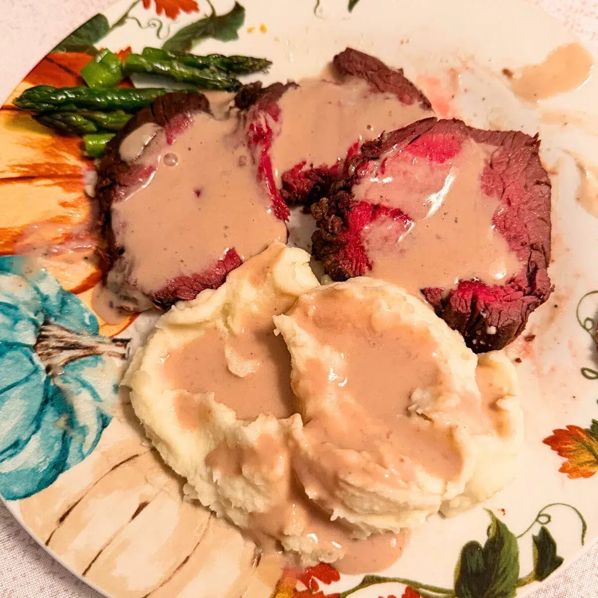 Beef tenderloin sauce on a decorative plate of beef tenderloin and mashed potatoes.
