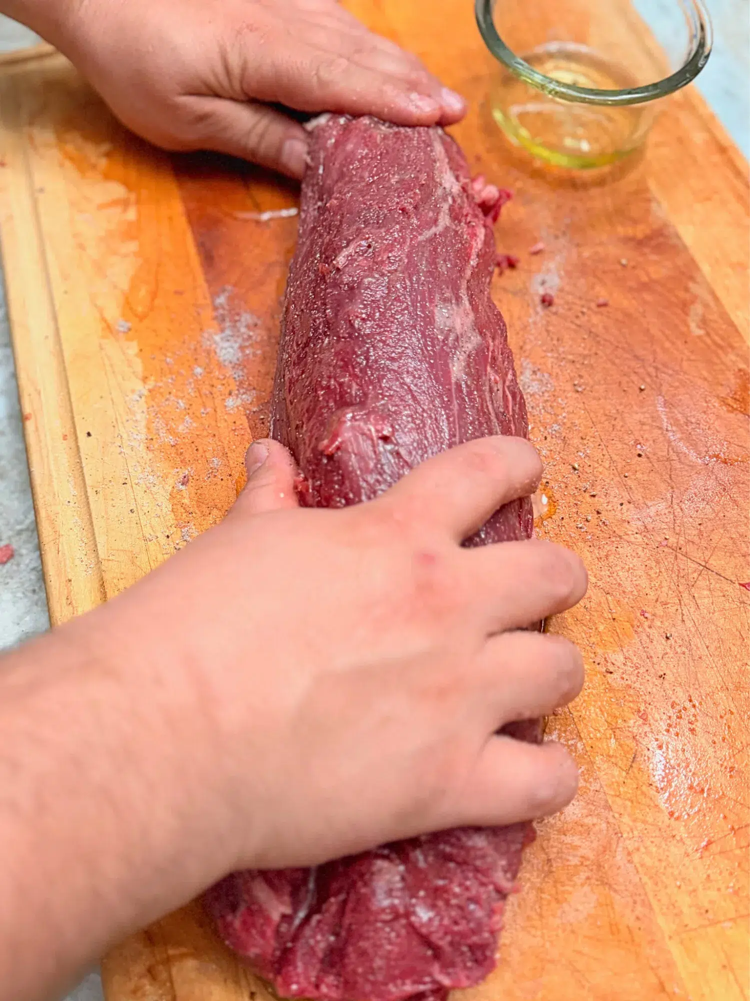 Rubbing oil on a whole beef tenderloin.