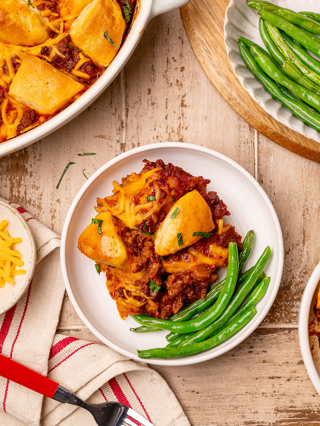 A serving of sloppy joe biscuit bake served with a side of green beans.