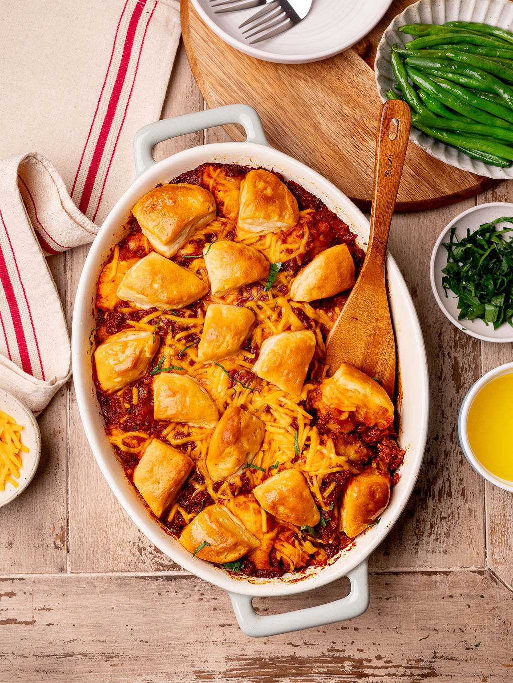 Sloppy joe biscuit bake in a baking dish over a rustic wooden surface.