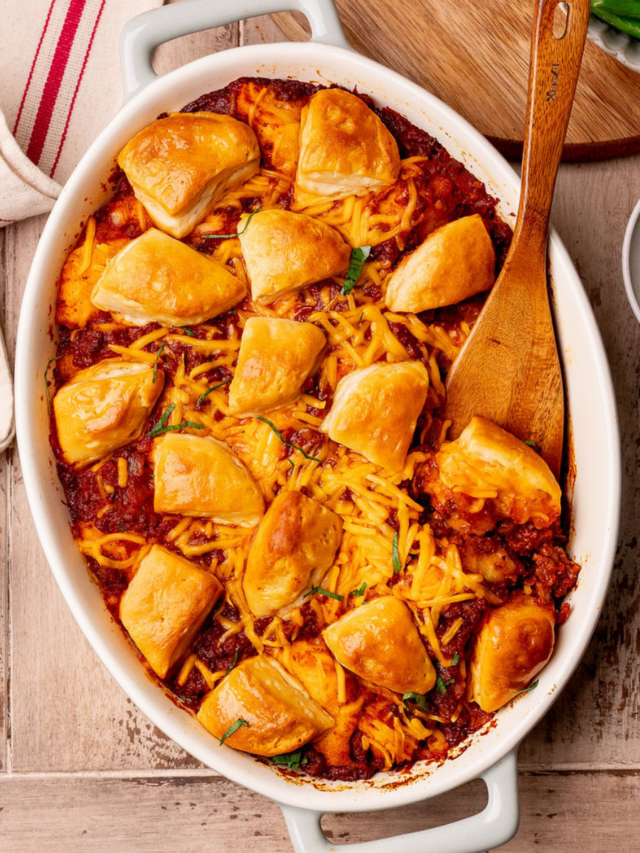 Sloppy joe biscuit bake in a baking dish over a rustic wooden surface.