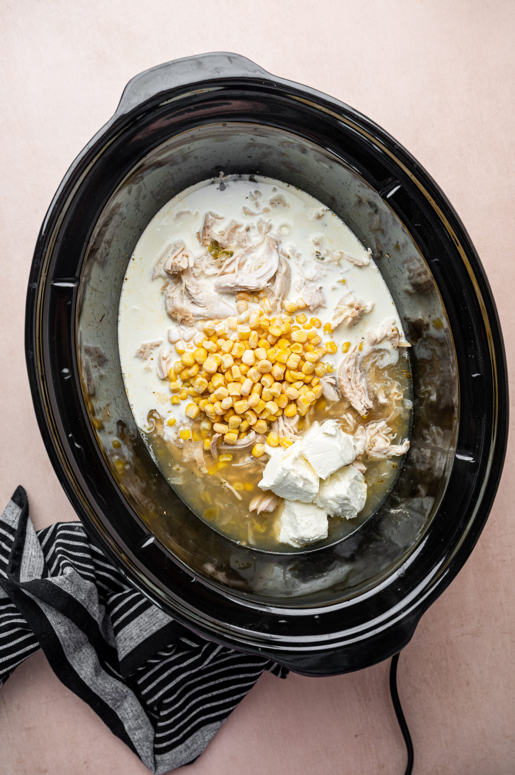 Corn, chicken, broth, and heavy cream in a slow cooker.