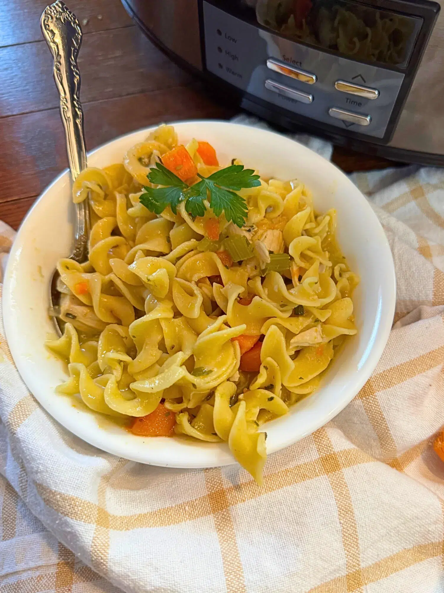 Slow cooker chicken noodle soup in a white bowl.
