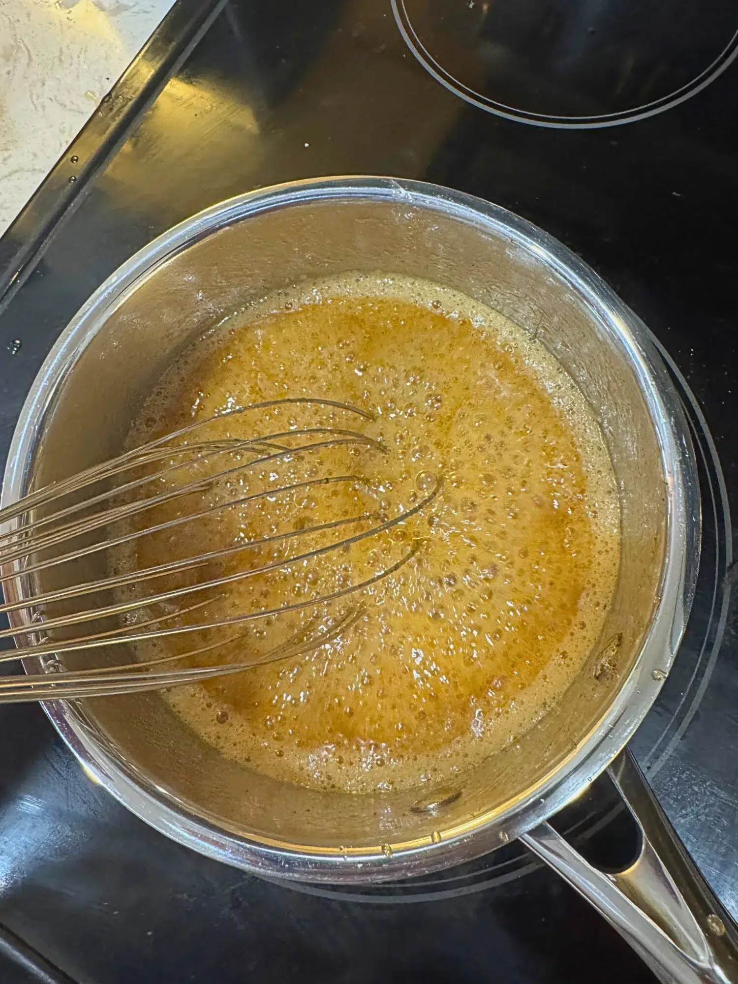 Honey glaze for slow cooker ham bubbling over the stove.