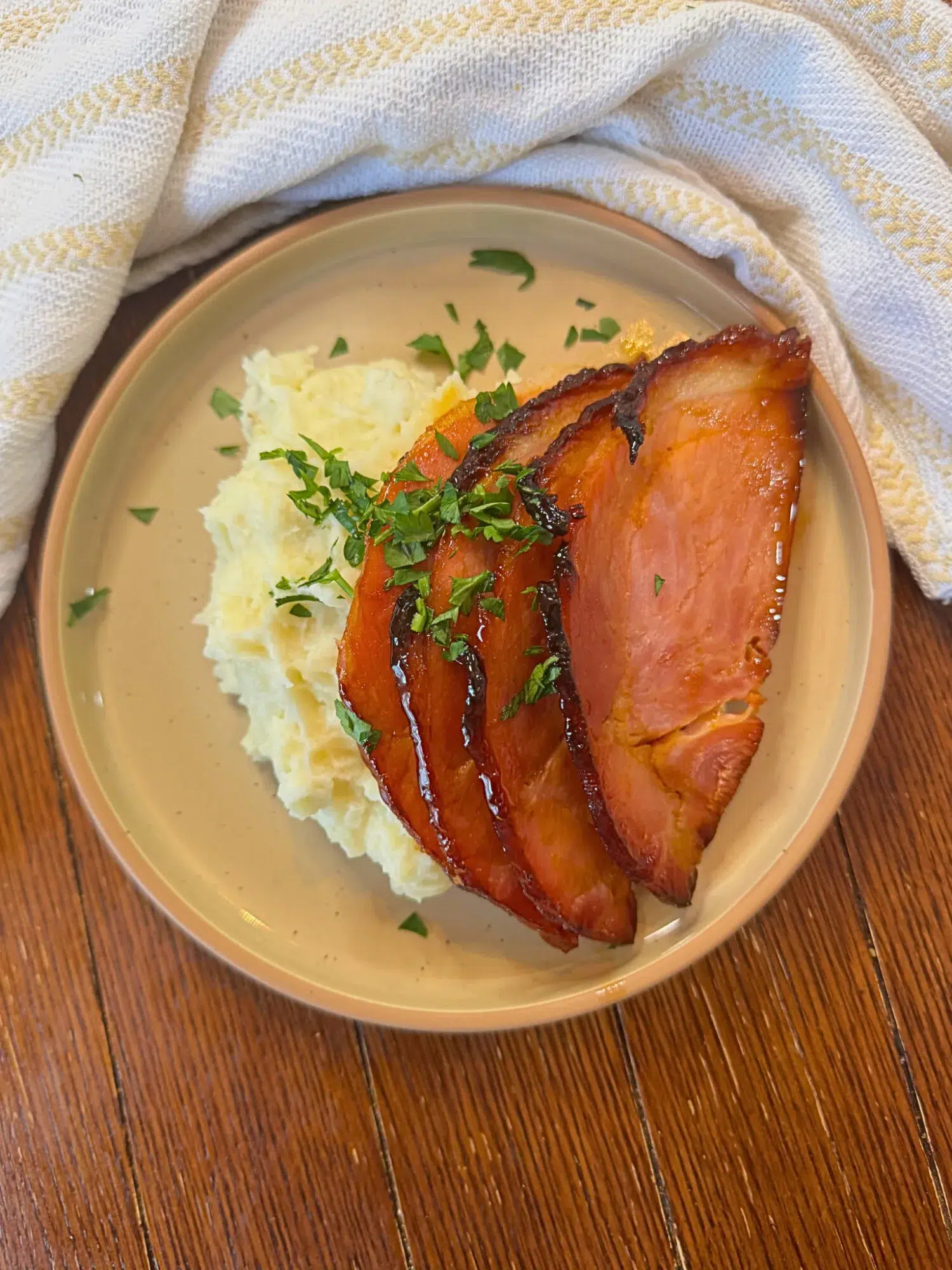 A plate of slow cooker honey glazed ham with mashed potatoes.