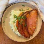 A plate of slow cooker honey glazed ham with mashed potatoes.