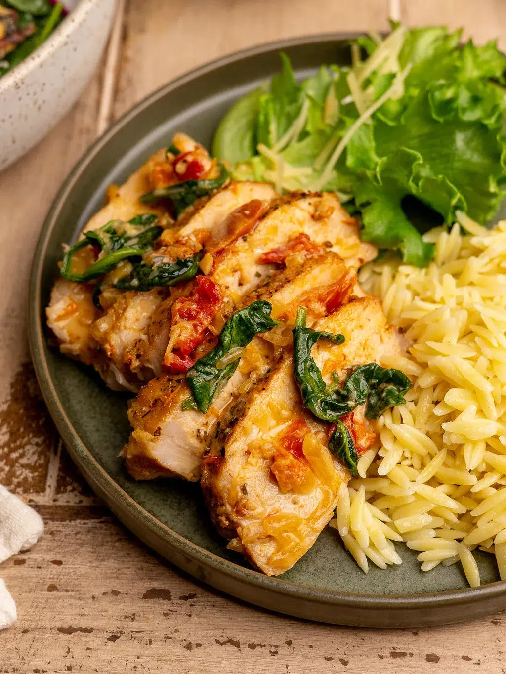 Close-up of slow cooker Tuscan pork tenderloin on a plate with a side of rice and greens.