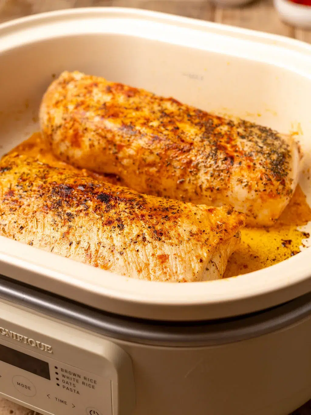 Two seared pork tenderloins in a slow cooker.