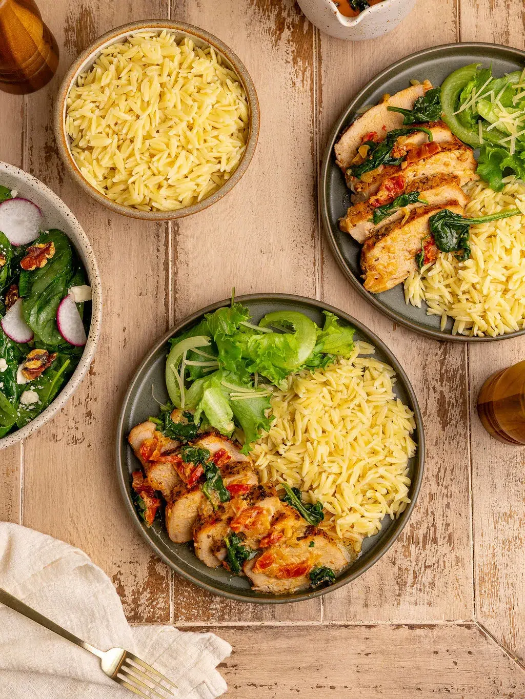 Three servings of slow cooker Tuscan pork tenderloin on plates over a light wooden surface.