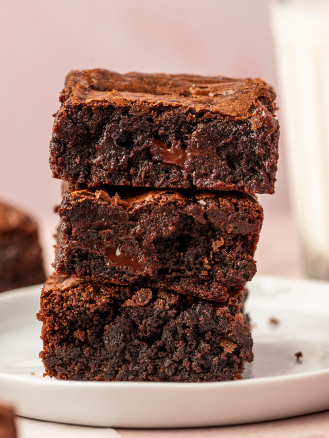 A stack of fudgy brownies on a white plate.
