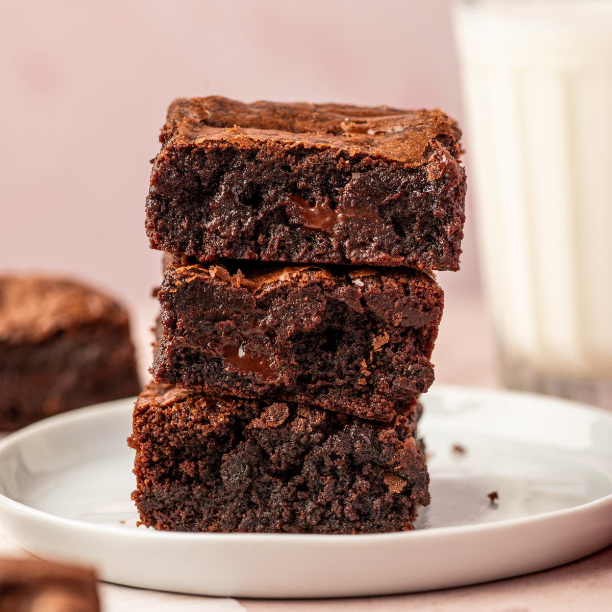 A stack of fudgy brownies on a white plate.