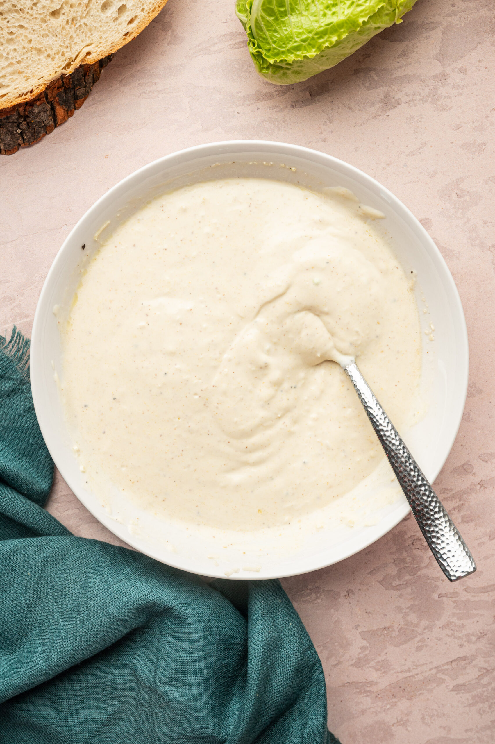 Dressing for Caesar chicken salad in a white bowl with a spoon.