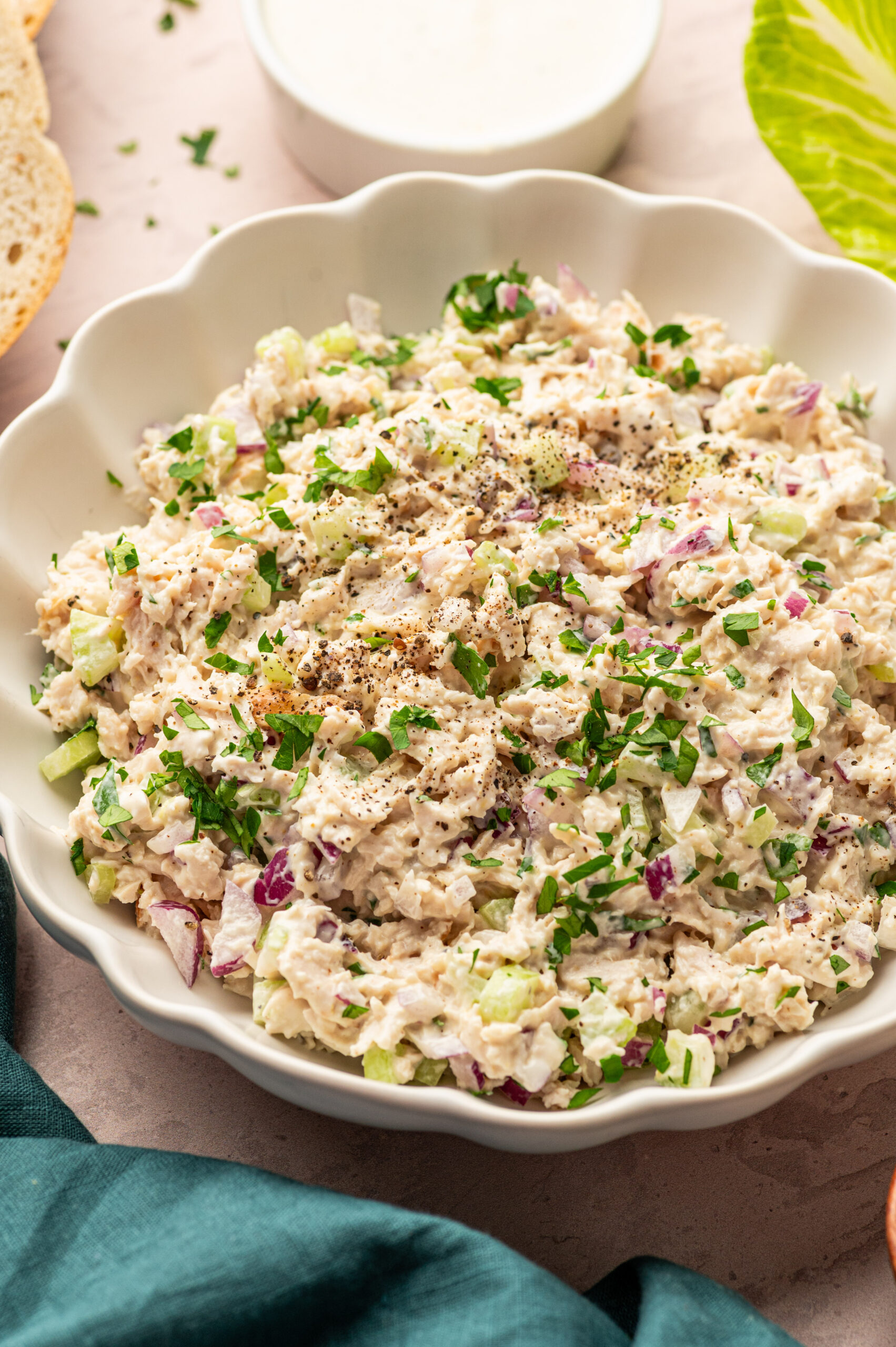 Creamy Caesar Chicken salad in a white serving dish garnished with fresh parsley.