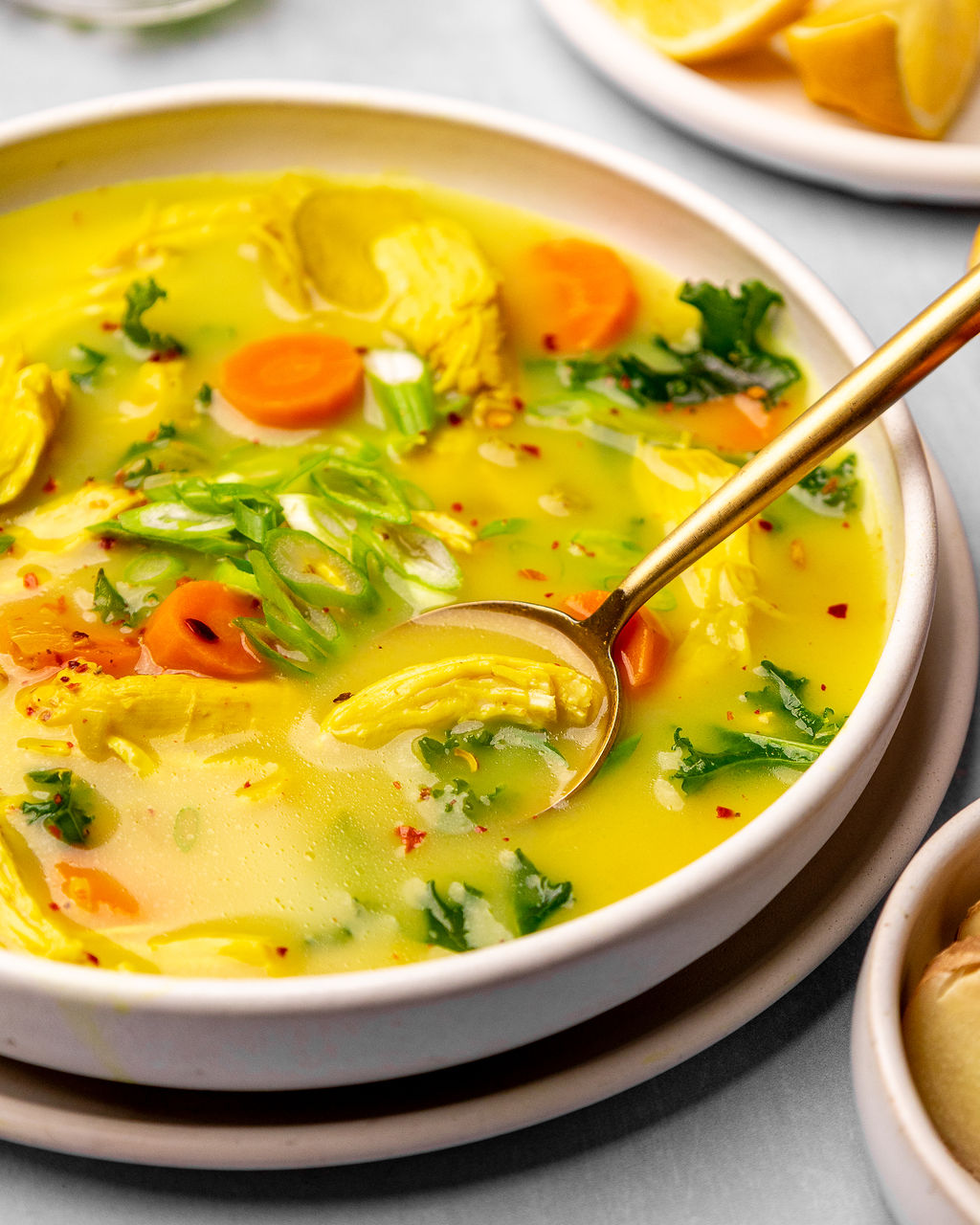 Close-up of immunity chicken soup in a white bowl with a spoon.