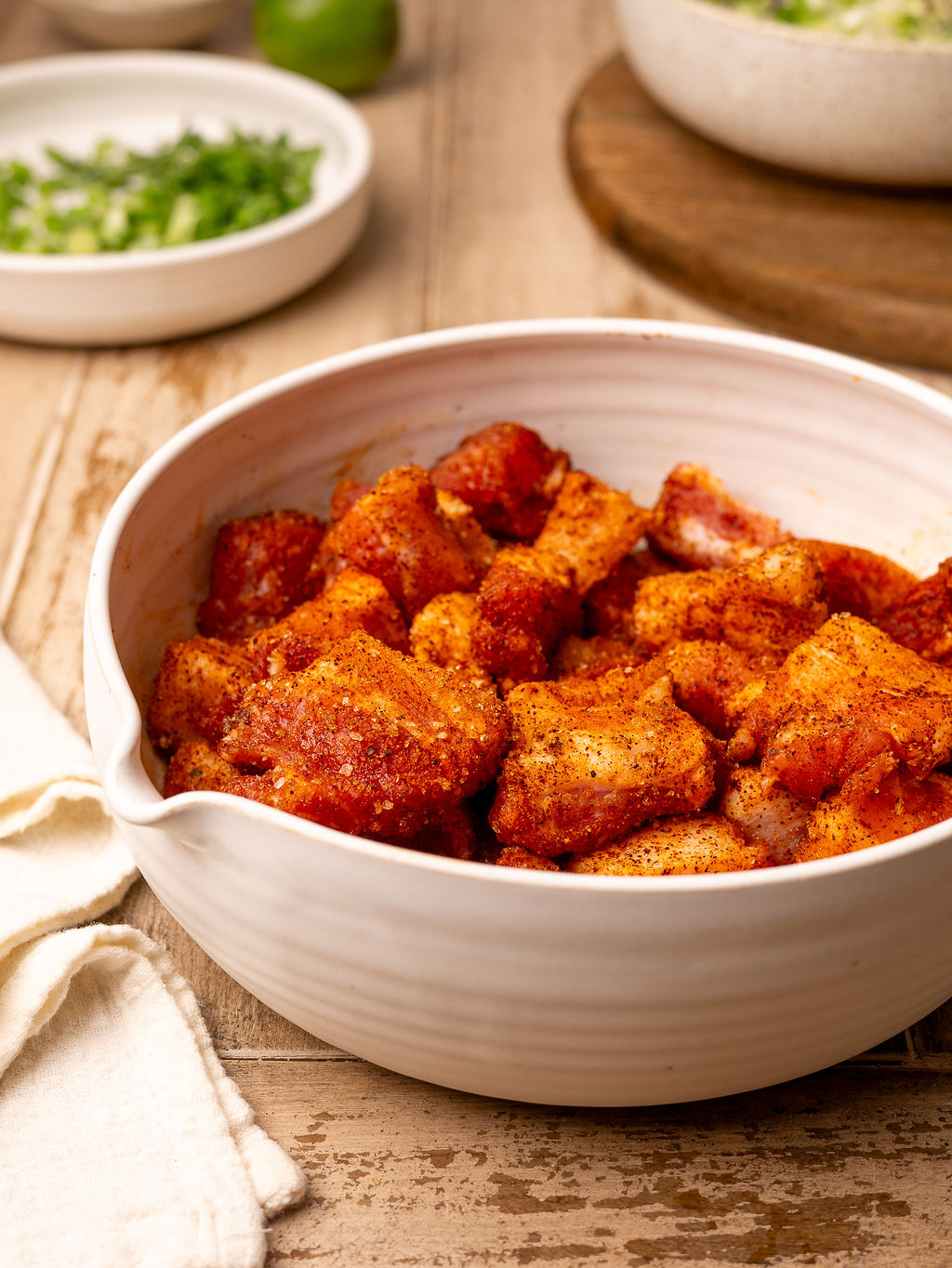 Seasoned pork belly pieces in a white mixing bowl.