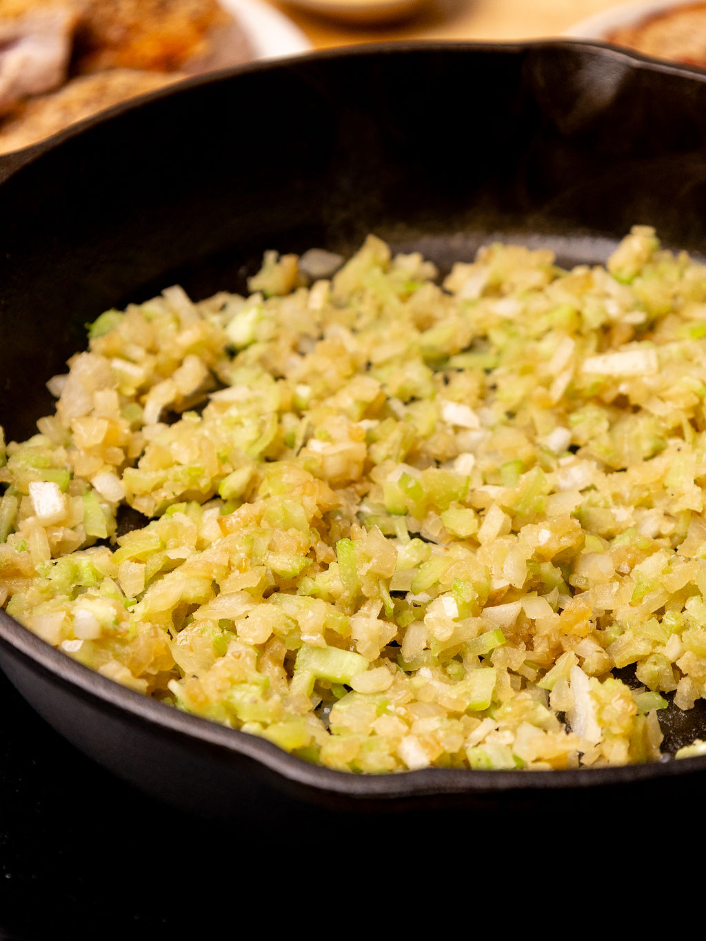 Onion and celery sauteing in a skillet.