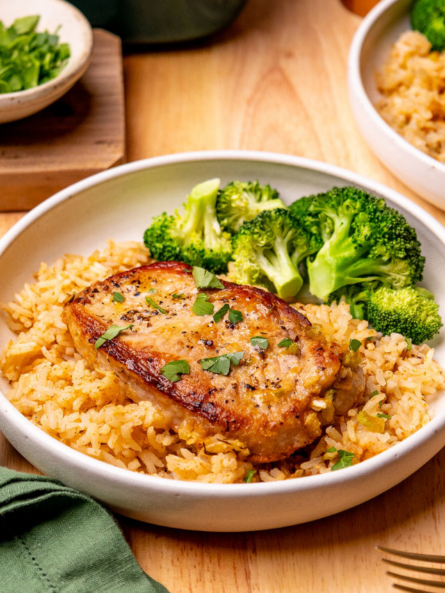 A serving of my pork chop and rice casserole on a white plate with a side of broccoli.