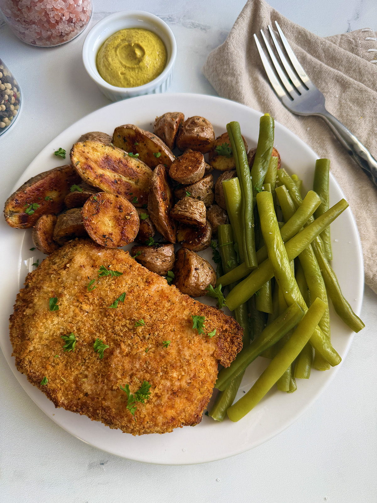 Delicious breaded pork chops served with roasted potatoes and green beans.
