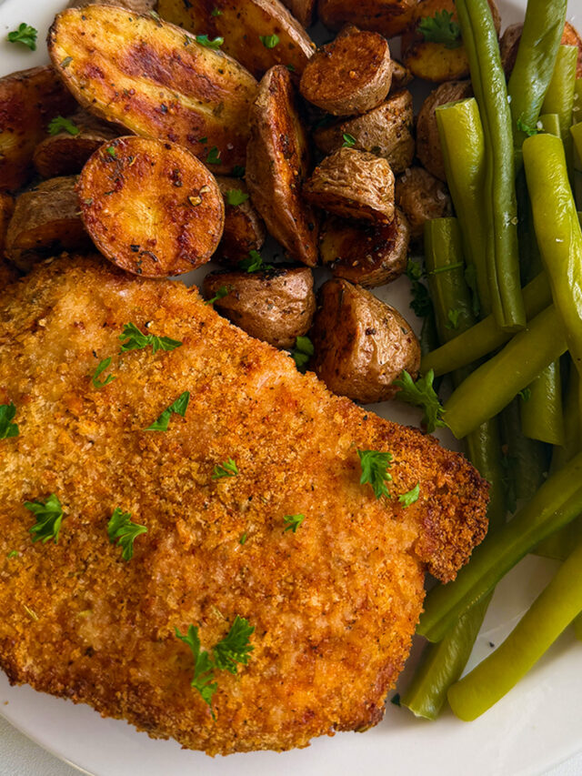 Breaded air fryer pork chops served with roasted potatoes and green beans.