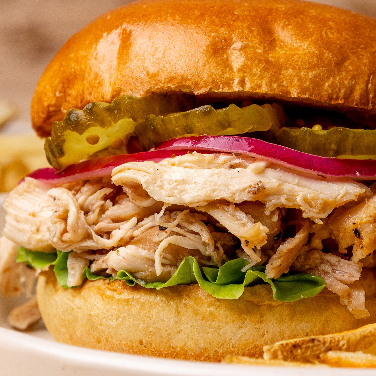Slow cooker pulled chicken being served on a bun.