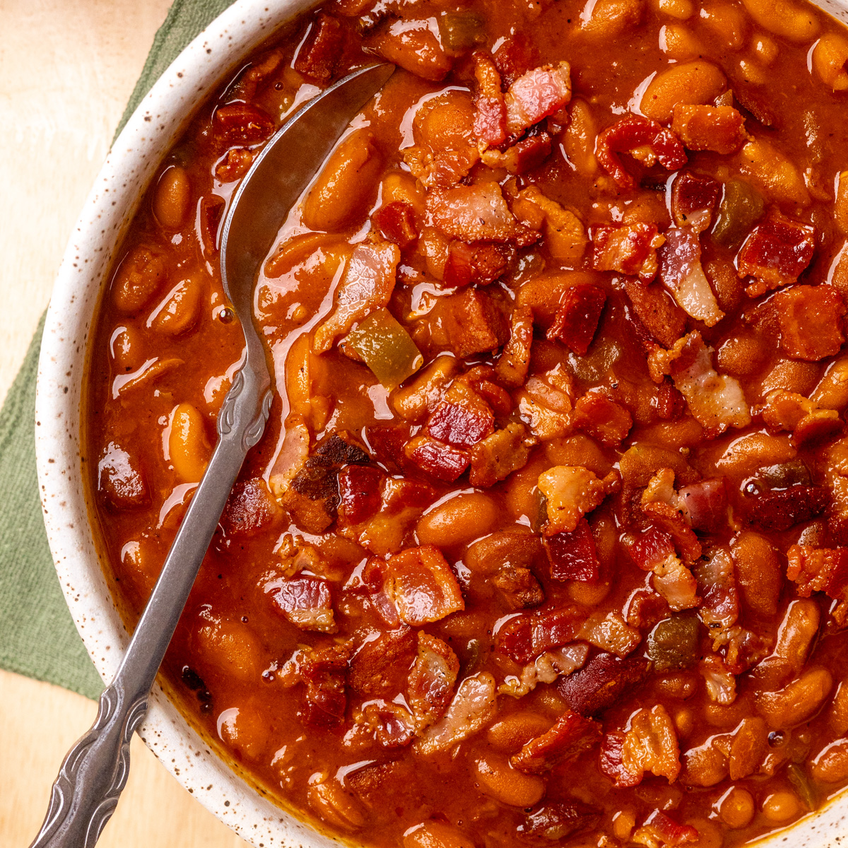 BBQ baked beans, made from scratch, served in a bowl with a serving spoon.